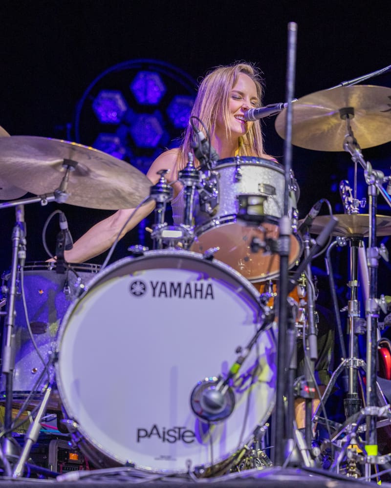 Drummer performs at a kit bathed in blue stage lighting during The Corrs 2023 Australian Tour.