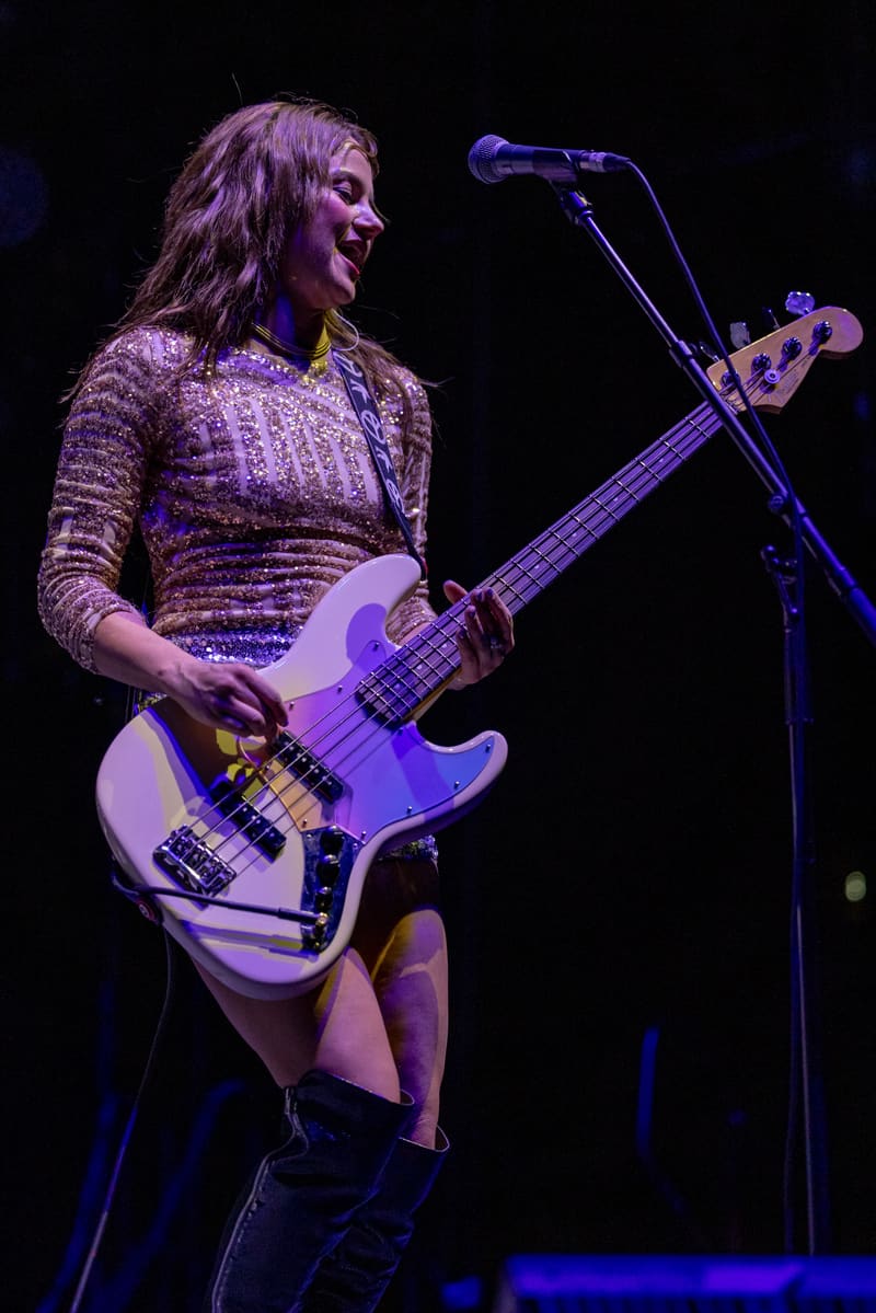 Bass guitarist performs on stage under purple stage lighting during The Corrs 2023 Australian tour.