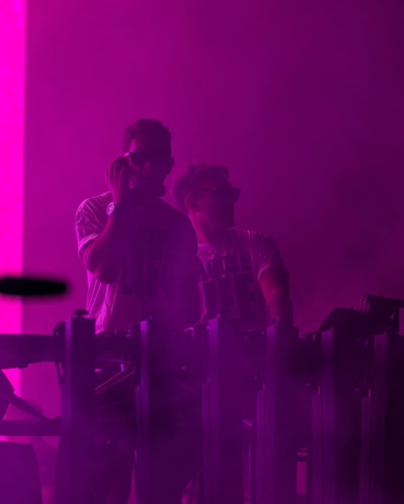 Two performers on stage bathed in intense magenta lighting at Harvest Rock Festival 2023.