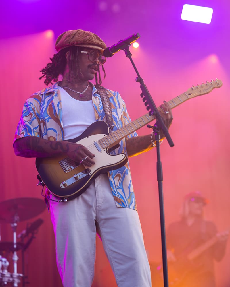 Guitarist performing at Harvest Rock Festival 2023, bathed in vibrant pink and purple stage lighting.