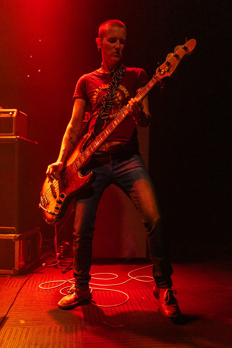 Bassist performing on stage bathed in red lighting during Jebediah's Gum Up The Bearings 2023 Tour.