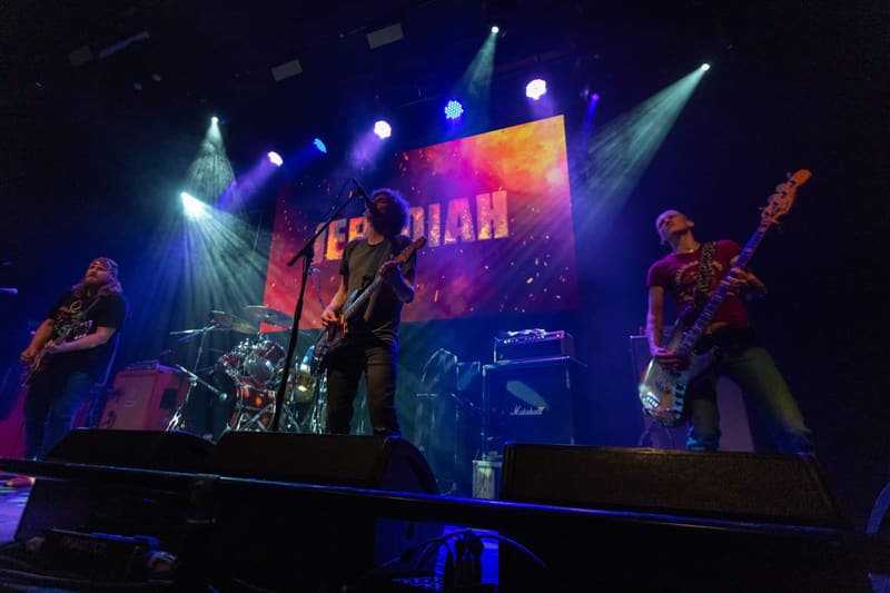 Band performing on stage with colourful lighting and large screen displaying "Jebediah" during 2023 tour.