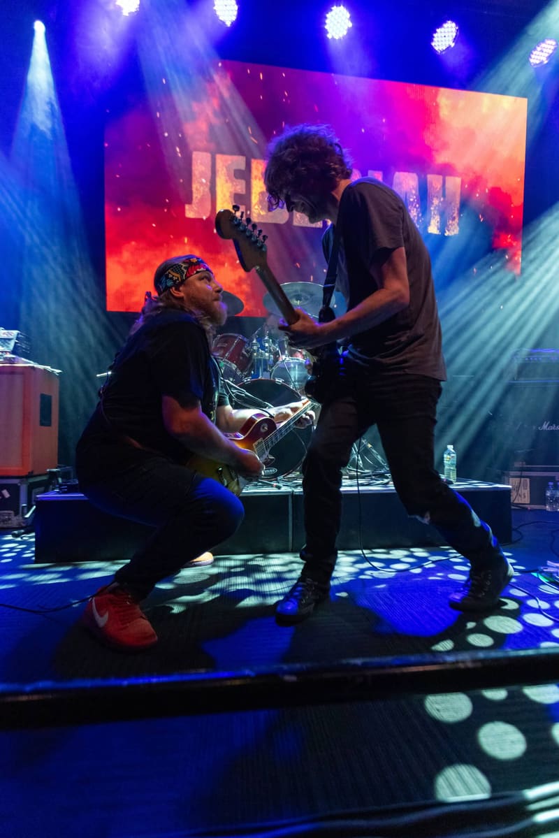 Two musicians perform on stage beneath vibrant pink and blue lighting during the Jebediah Gum Up The Bearings 2023 Tour.