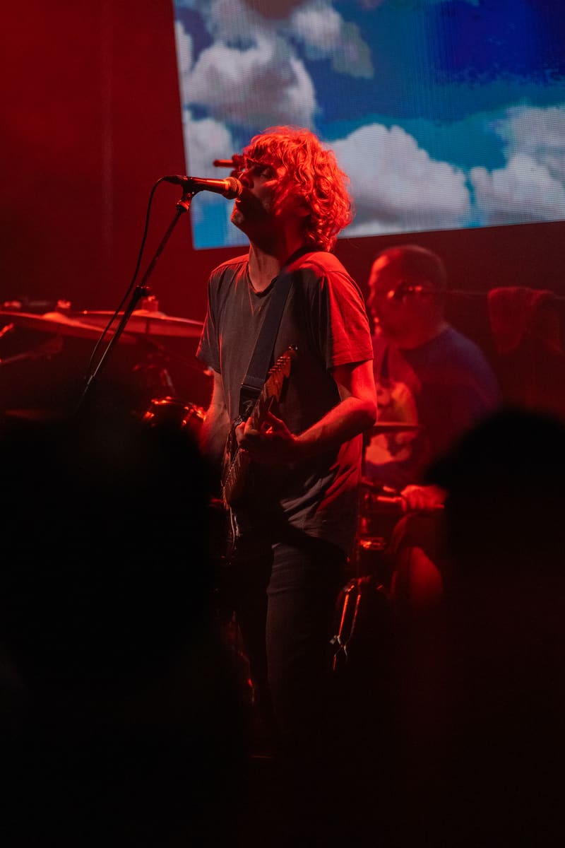 Musician singing at microphone bathed in red stage light during Jebediah's Gum Up The Bearings 2023 tour.