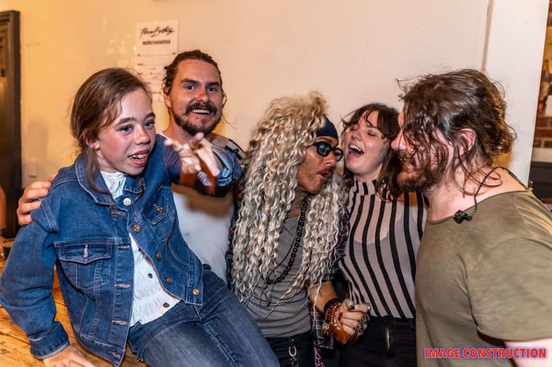 Five people gather closely together in a warm-lit indoor space, smiling at the camera during the Pierce Brothers Moonrise 2026 Album Tour.
