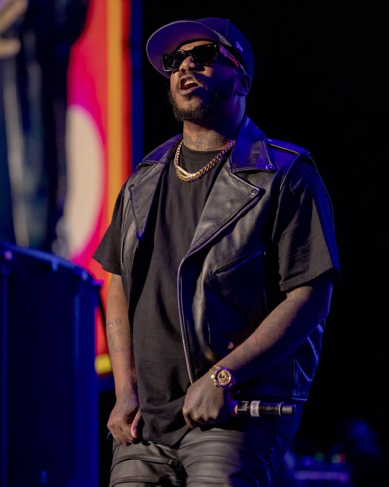 Performer wearing cap and black shirt on stage lit by coloured spotlights at 112 – Fridayz Live.