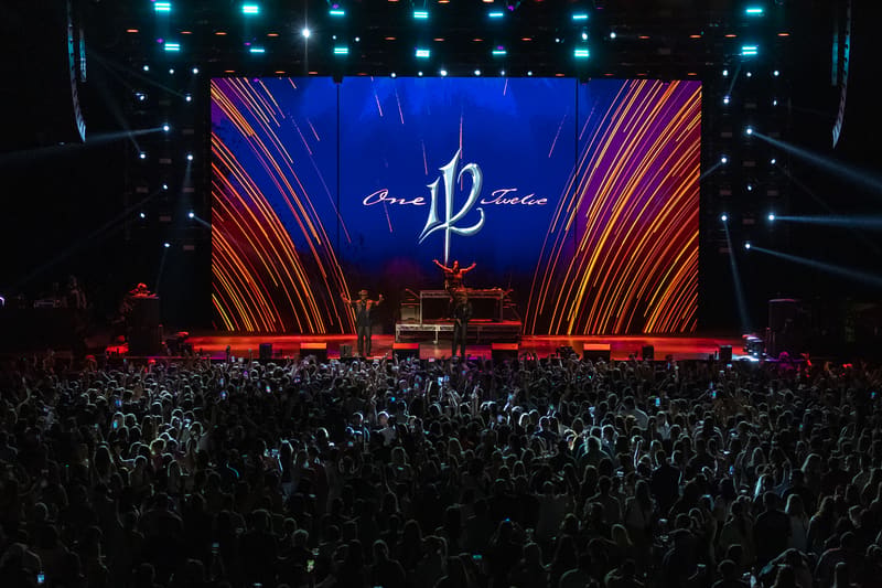 Large crowd faces a stage with glowing blue and orange geometric backdrop displaying "112" logo at Fridayz Live venue.