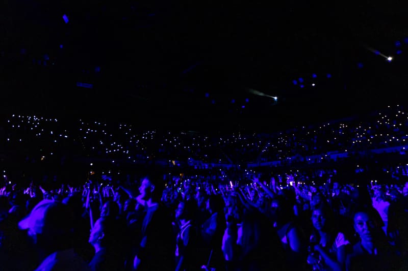 Large crowd bathed in blue stage lighting at a live music event venue.
