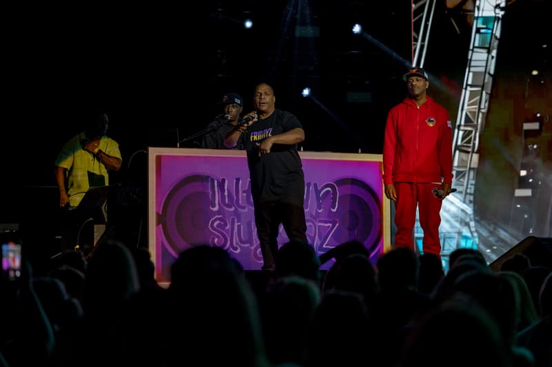 Three performers on stage with neon purple signage and a crowd visible in foreground during Illtown Sluggaz – Fridayz Live.