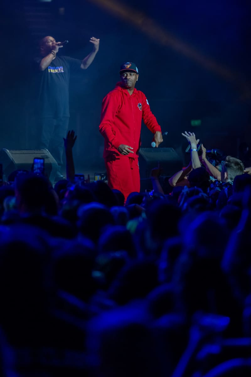 Two performers on stage in vibrant clothing engaging with a crowd illuminated by blue stage lighting at Illtown Sluggaz – Fridayz Live.