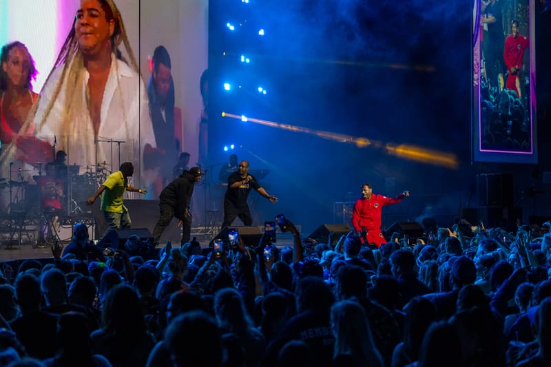 Performers in bright clothing command a blue-lit stage above a crowd with raised arms during Illtown Sluggaz – Fridayz Live.