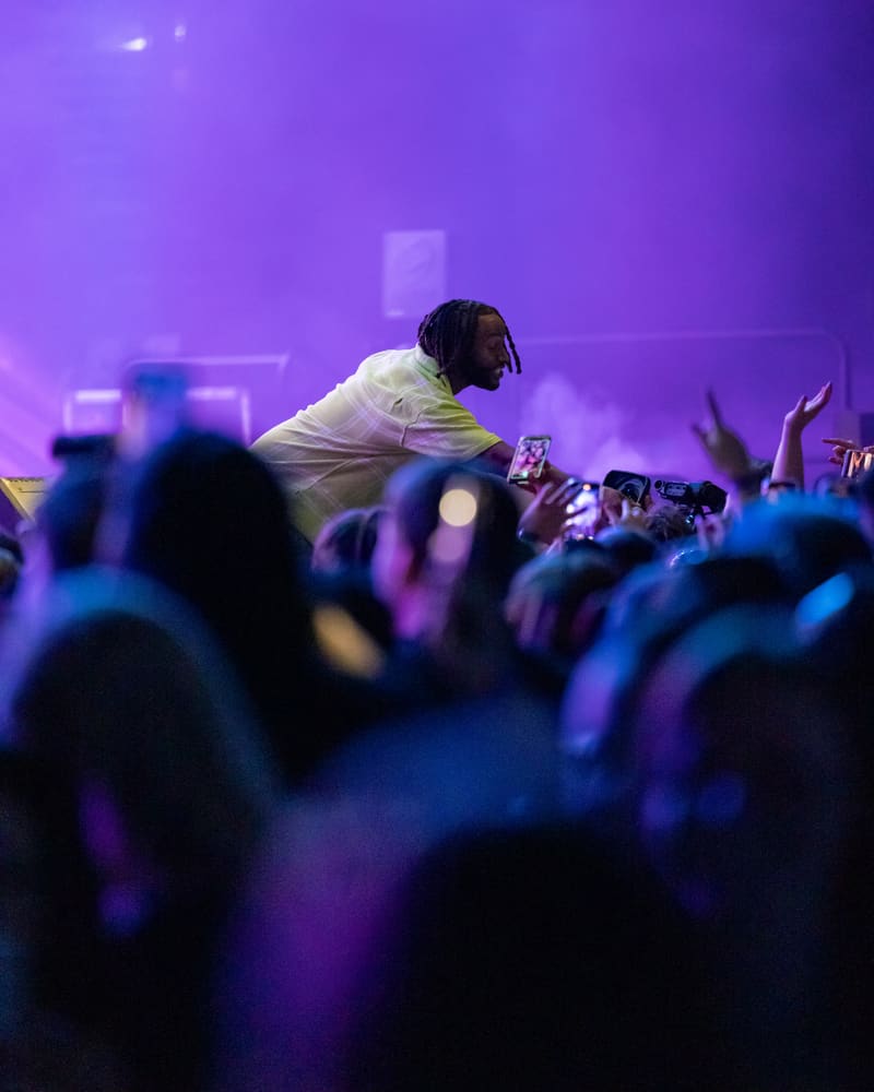 Performer leaning into crowd under purple stage lighting at Illtown Sluggaz – Fridayz Live event.