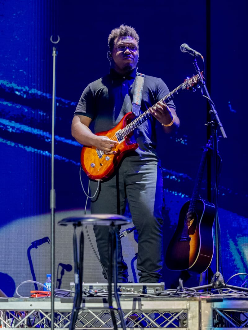 Guitarist performing with sunburst electric guitar under blue stage lighting at Fridayz Live.