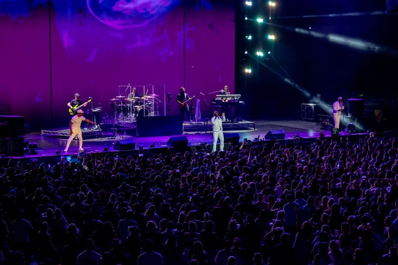 Multiple performers on stage under purple lighting with a large crowd in the foreground during Boyz II Men's Fridayz Live concert.