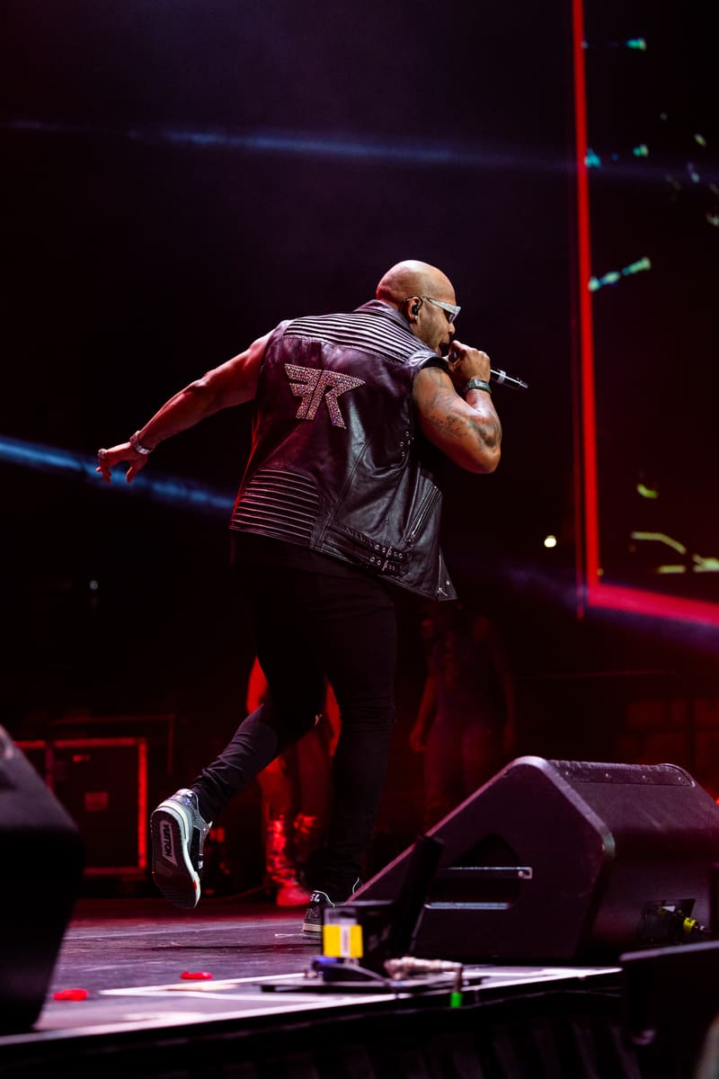 Performer singing into microphone on stage, lit by red and blue spotlights during a live concert.