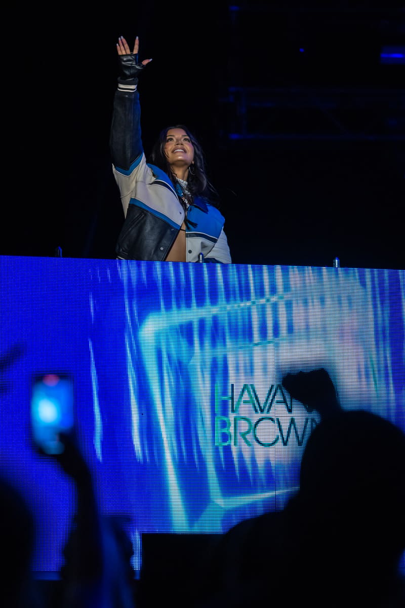 Performer on stage raising fist in triumph beneath blue stage lighting during live show.