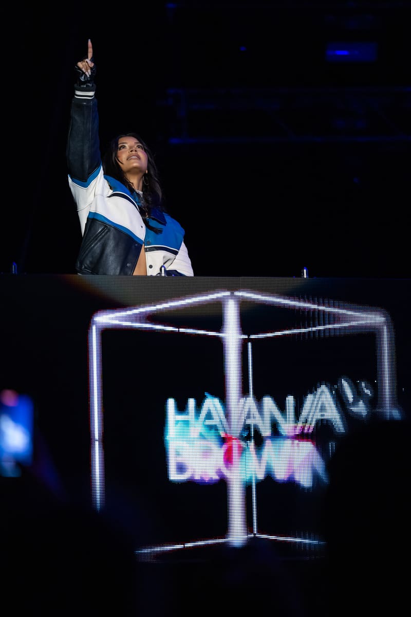 Havana Brown performs on stage with her fist raised, standing above a neon-lit cube displaying her name.