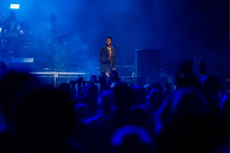 Performer on stage bathed in blue light, engaging with an enthusiastic crowd below.