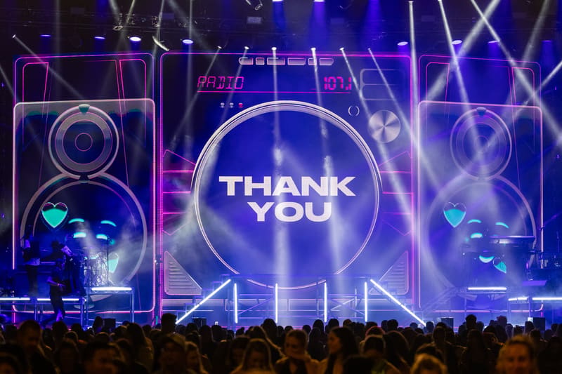 Stage display with "THANK YOU" message and neon-lit visuals during a concert performance.