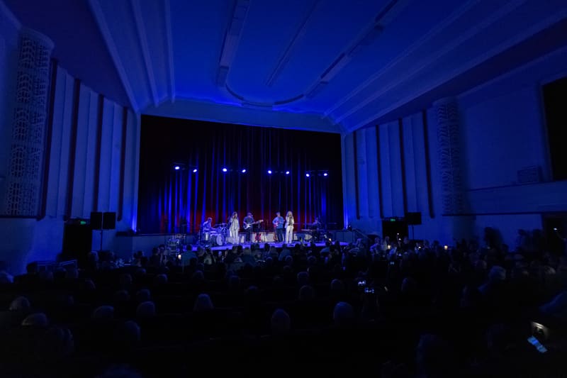 Band and audience silhouettes on stage bathed in blue lighting during a concert performance.
