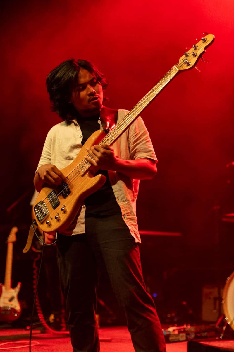 Bassist performs on stage bathed in red light during a Psychedelic Porn Crumpets concert.