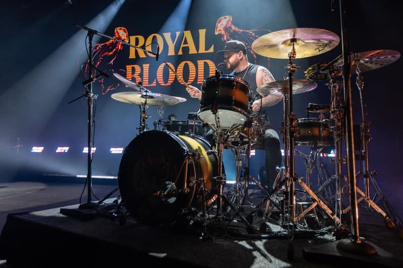Drummer performing on stage with Royal Blood logo and band name illuminated behind the kit.