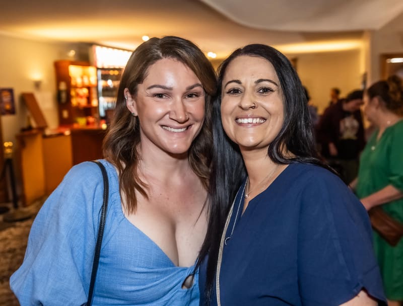 Two women smiling at the camera during a gallery opening at Shaun Holton & Friends.
